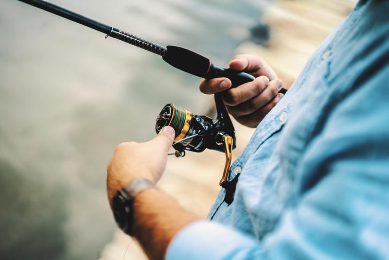 Man reeling in a fishing rod from a dock