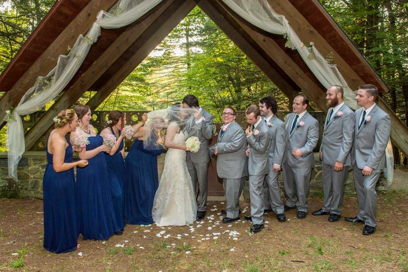 Bride and groom married in front of the chapel with their wedding party in the background