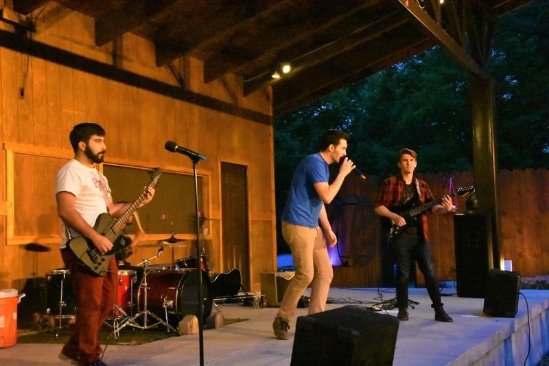 A band performing on stage in an amphitheater at dusk